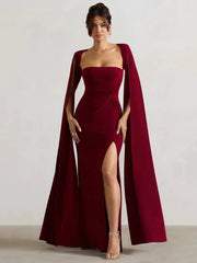 Model wearing a flowing cape sleeve maxi dress with a high split. 1