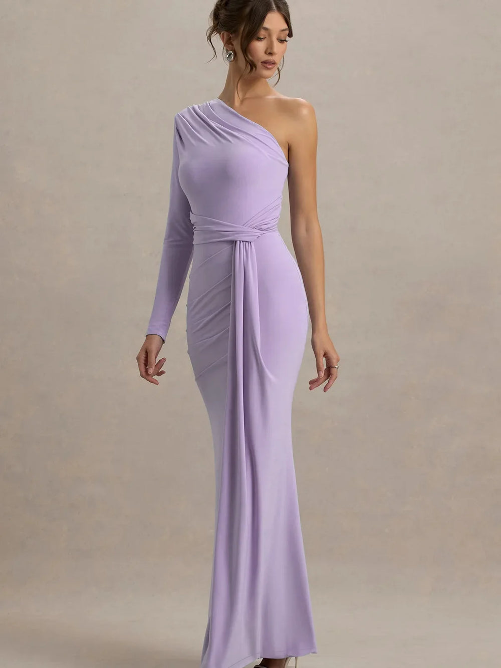 Woman wearing a one-shoulder lavender dress against a plain background