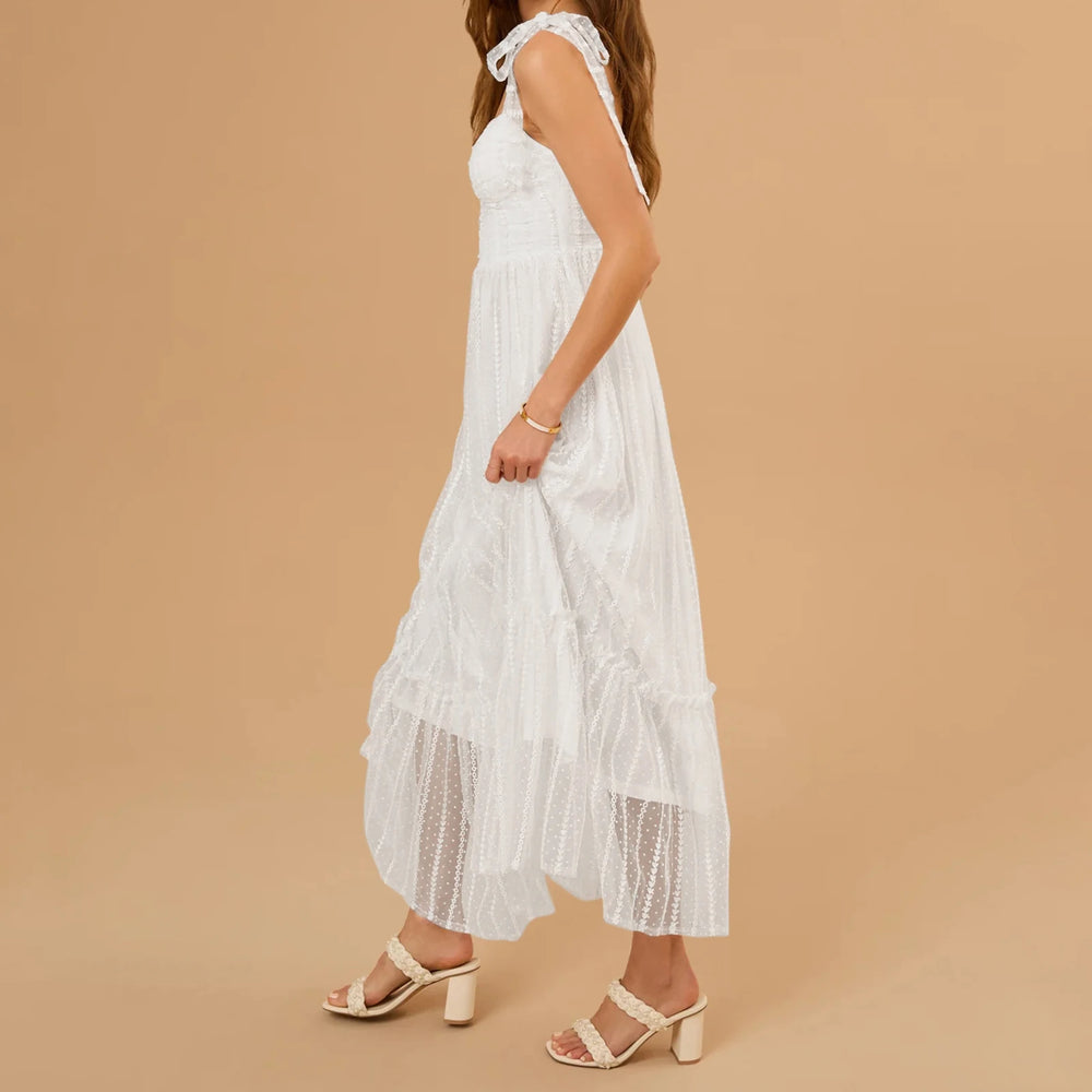 Woman wearing a white dress with ruffled details on a beige background