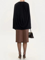 Person wearing a black top and brown skirt with fishnet tights and high heels 