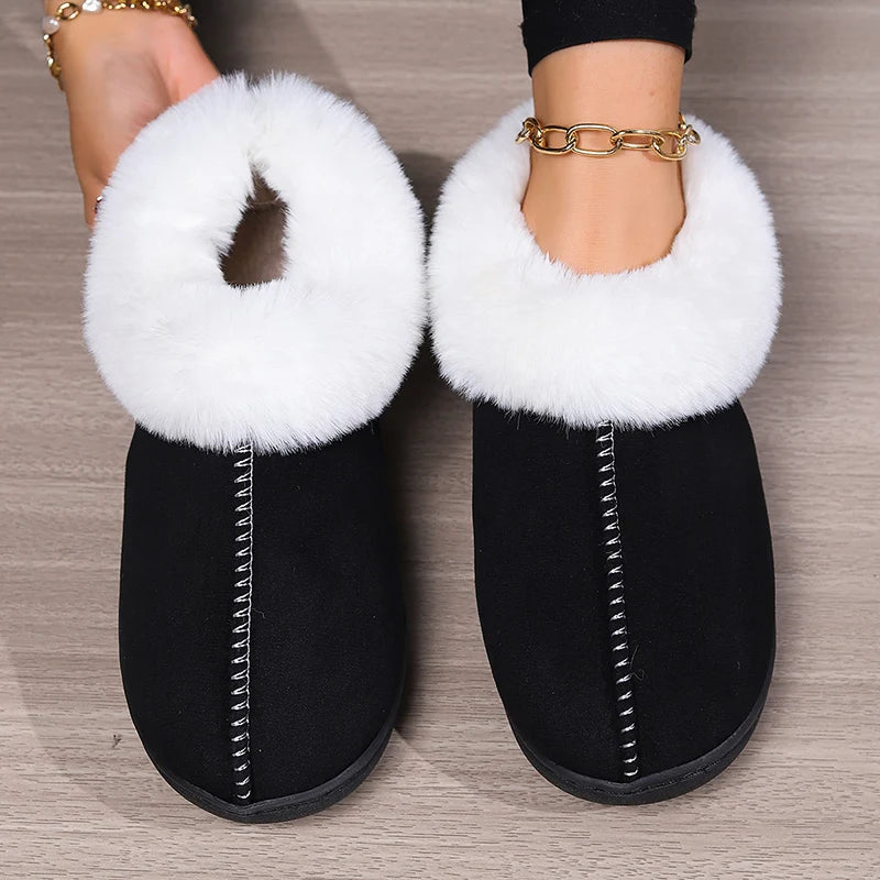 Black slippers with white fur trim on a wooden floor