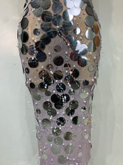 Mannequin wearing a dress covered in reflective sequins on a plain background