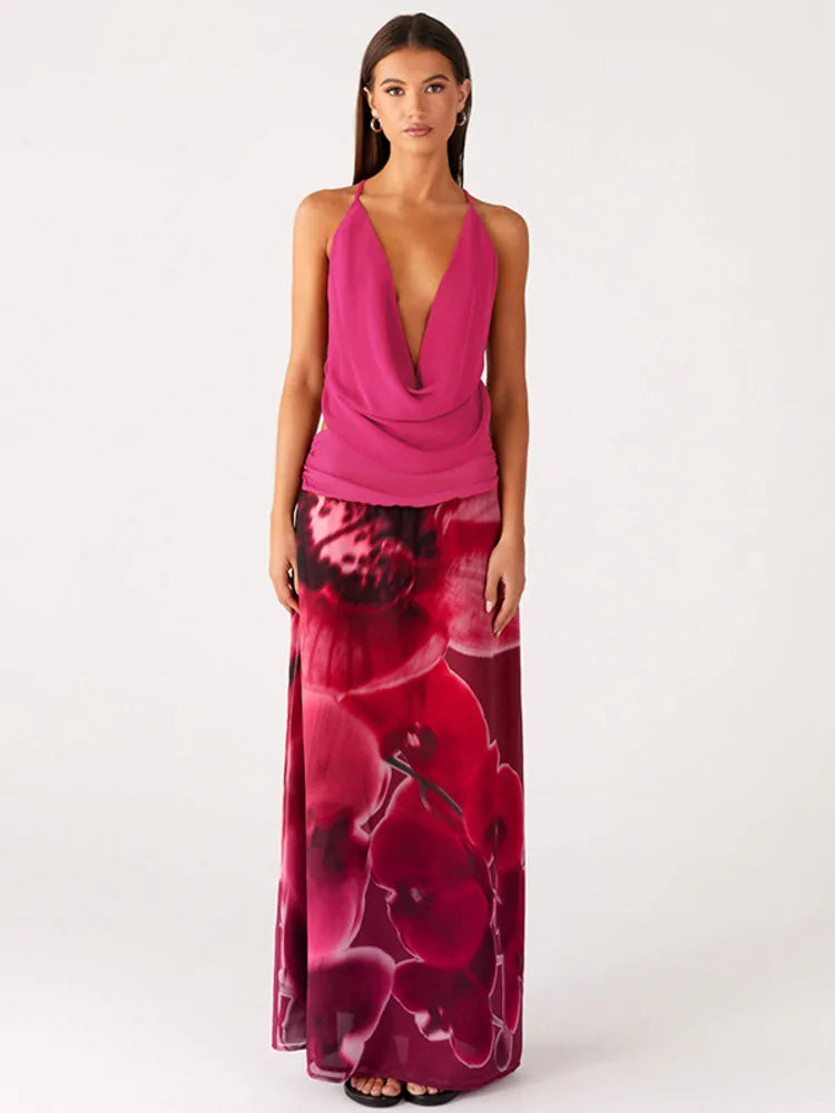 Woman wearing a deep V-neck cowl neck pink top and a floral print maxi skirt against a white background.