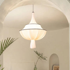 A soft, warm glow emanates from a vintage-style French fabric pendant light hanging in a minimalist living room. A