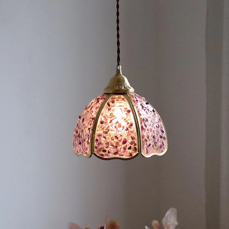 Pendant light with pink glass shade against a gray background