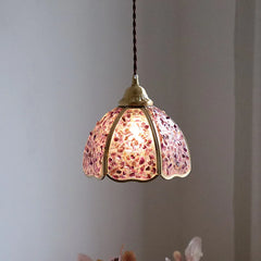 Pendant light with pink glass shade against a gray background