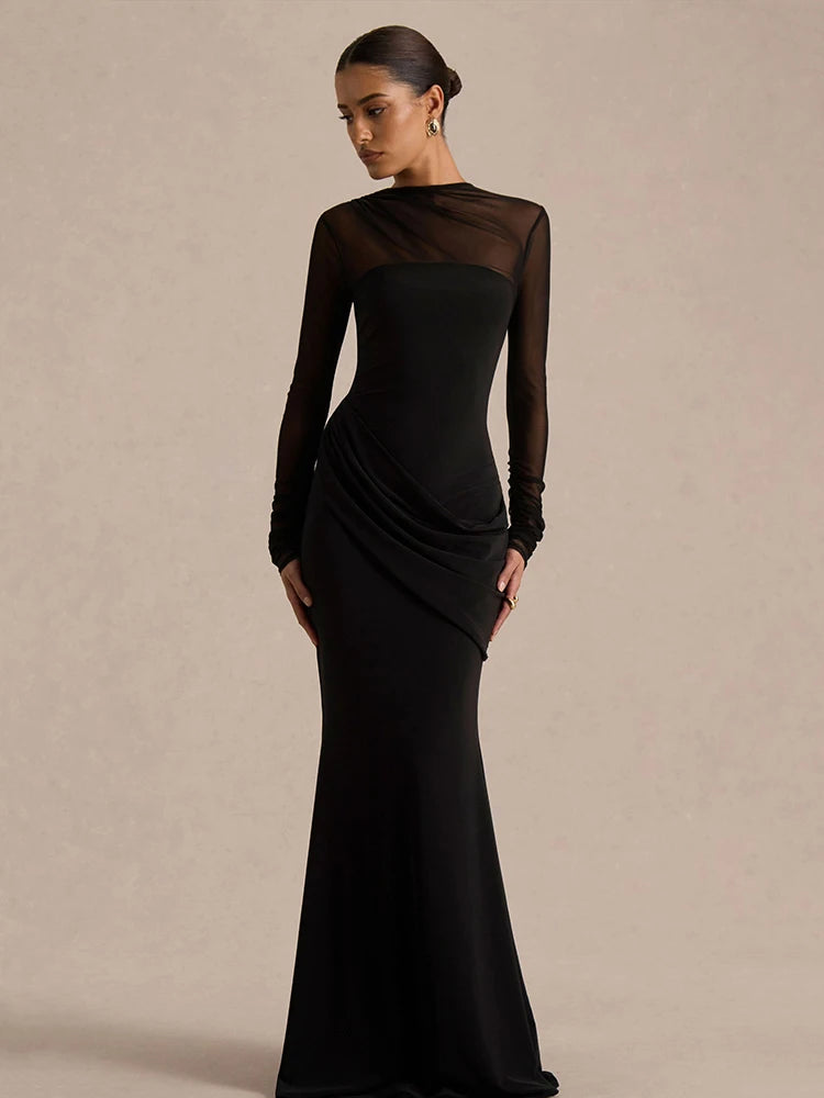 Woman wearing a black evening gown with sheer sleeves against a beige background