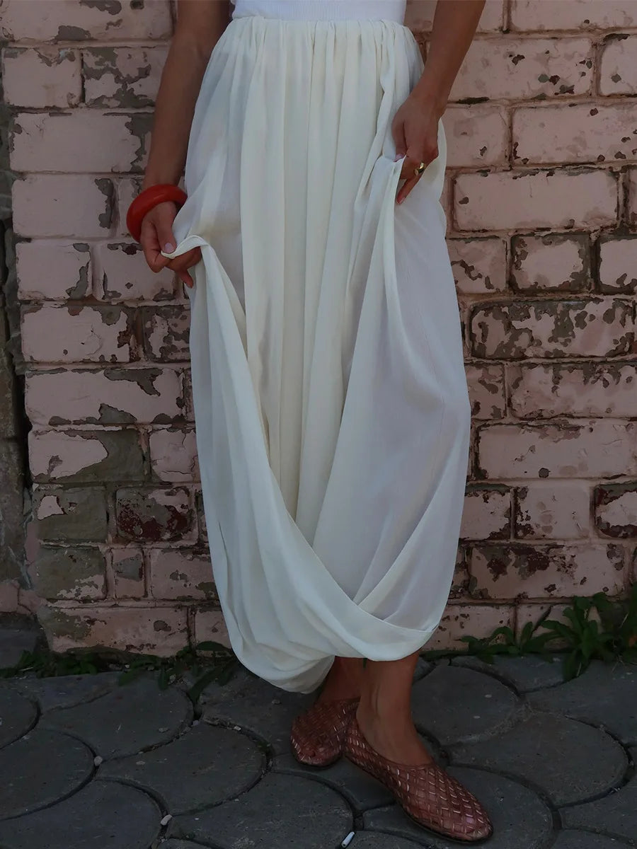 Person wearing a flowing white skirt against a brick wall.