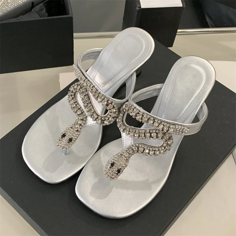 Silver sandals with rhinestone embellishments on a black surface
