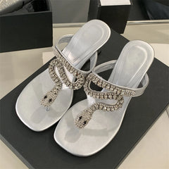 Silver sandals with rhinestone embellishments on a black surface