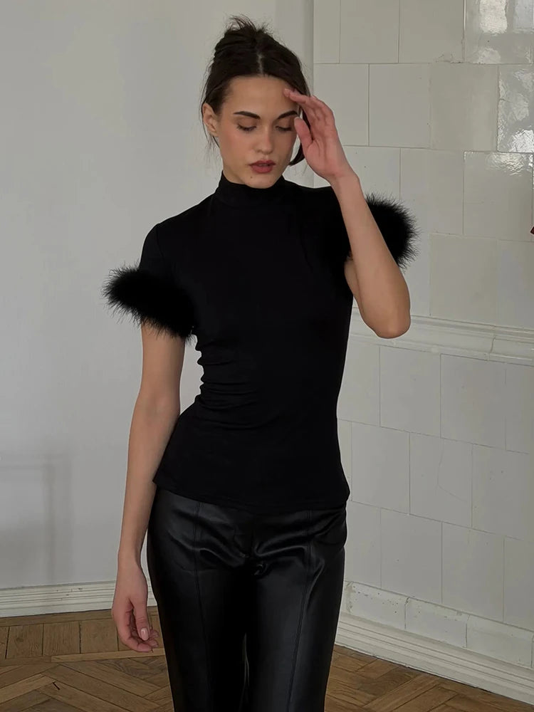 Woman wearing a black outfit with fur accents in a room with white tiled walls.
