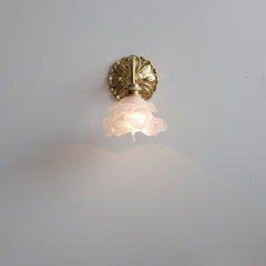 A wall-mounted pink  flower opaque glass shade in a copper color with a decorative element at the top, illuminated with an LED bulb.