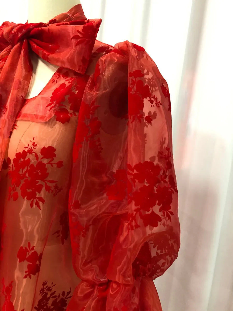 Red floral dress on a mannequin against a white curtain background