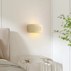 A French cream pumpkin wall lamp casting a soft glow in a cozy bedroom with a rustic wood headboard. C