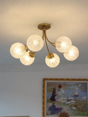 A modern glass ball ceiling light fixture hanging in a stylish living room. Golden Atelier 3