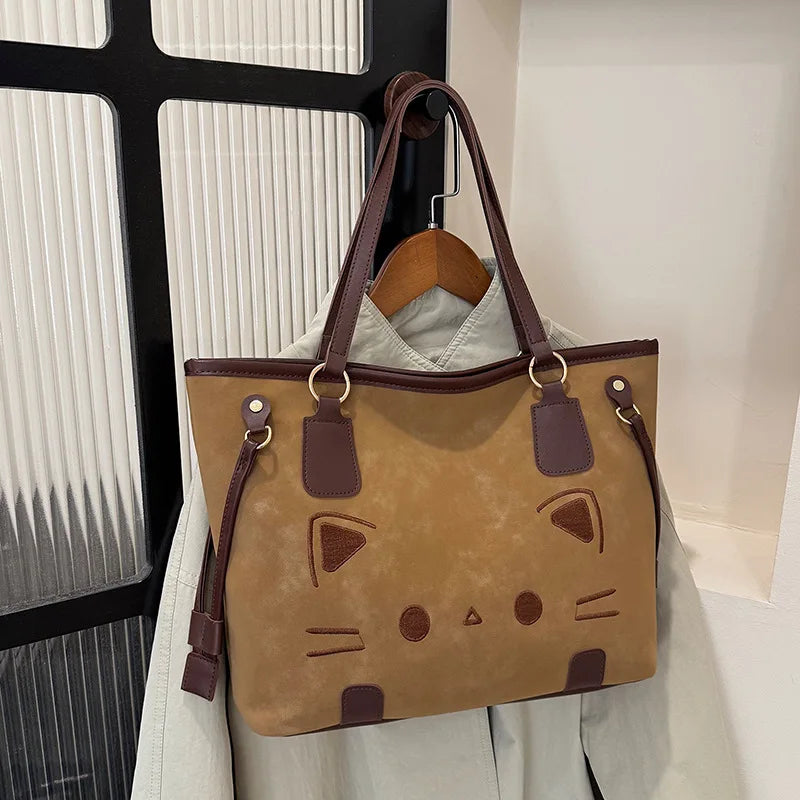 Brown suede-like tote bag with a cat face design, hanging
