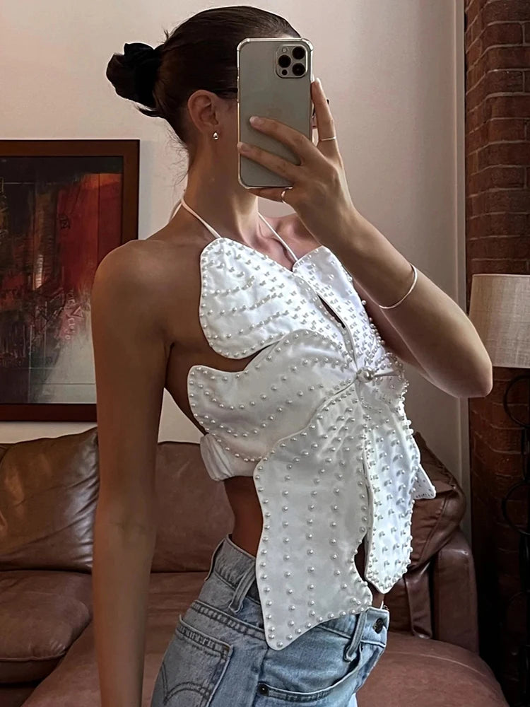 Person wearing a white blouse with butterfly sleeves in a room.