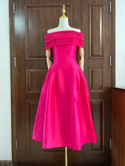 Hot pink off-shoulder dress on a mannequin against a wooden door.