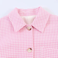 Close-up of a pink checkered shirt with a white collar on a light gray background