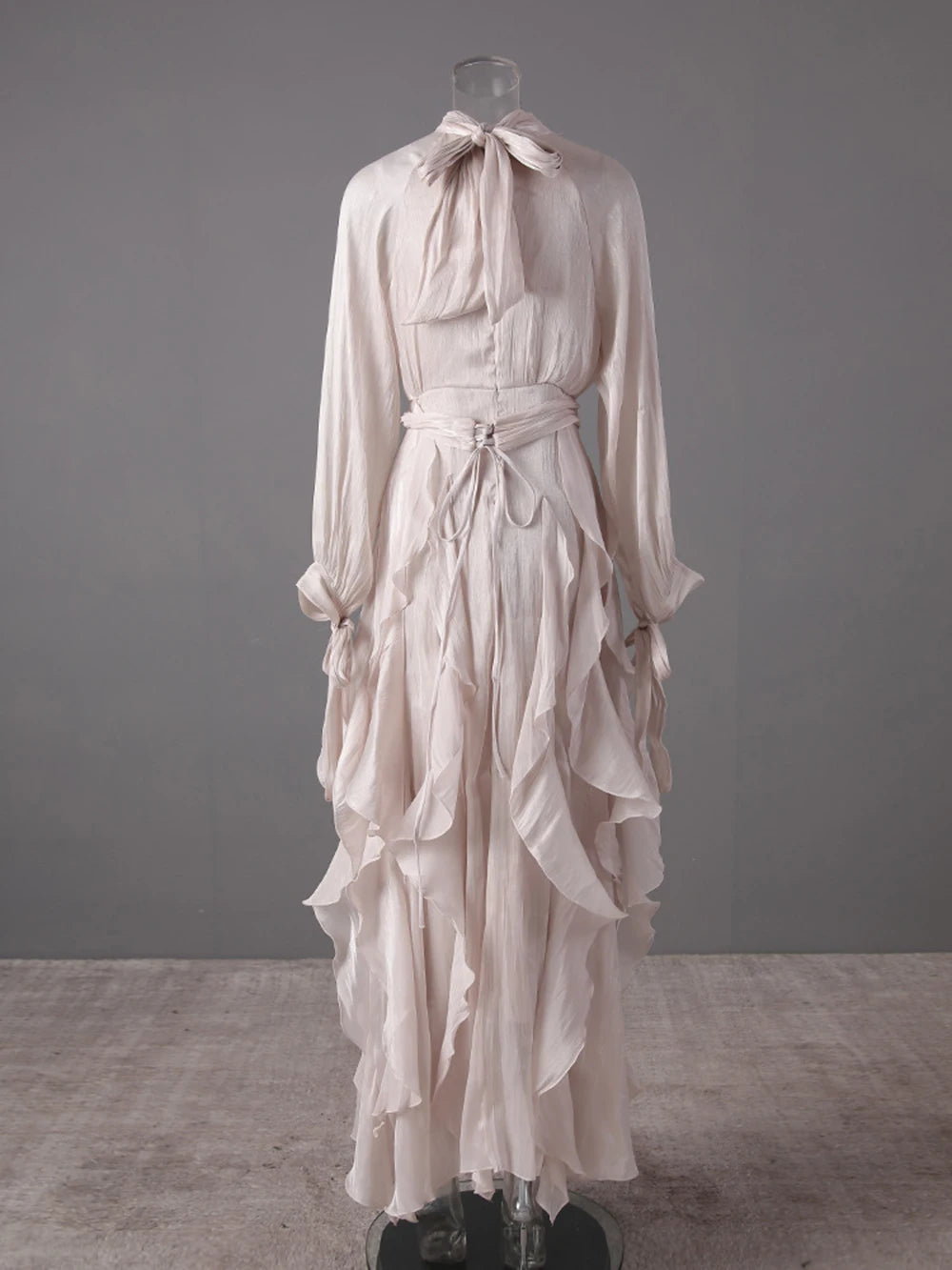Apricot dress with ruffled layers on a mannequin against a grey background