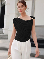 Woman wearing a black top and white pants standing outdoors.