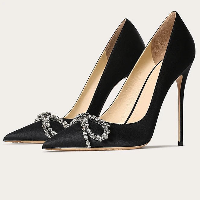 Black high-heeled shoes with decorative embellishments on a light gray background