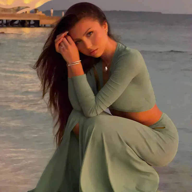 Woman in a green outfit sitting on a beach at sunset