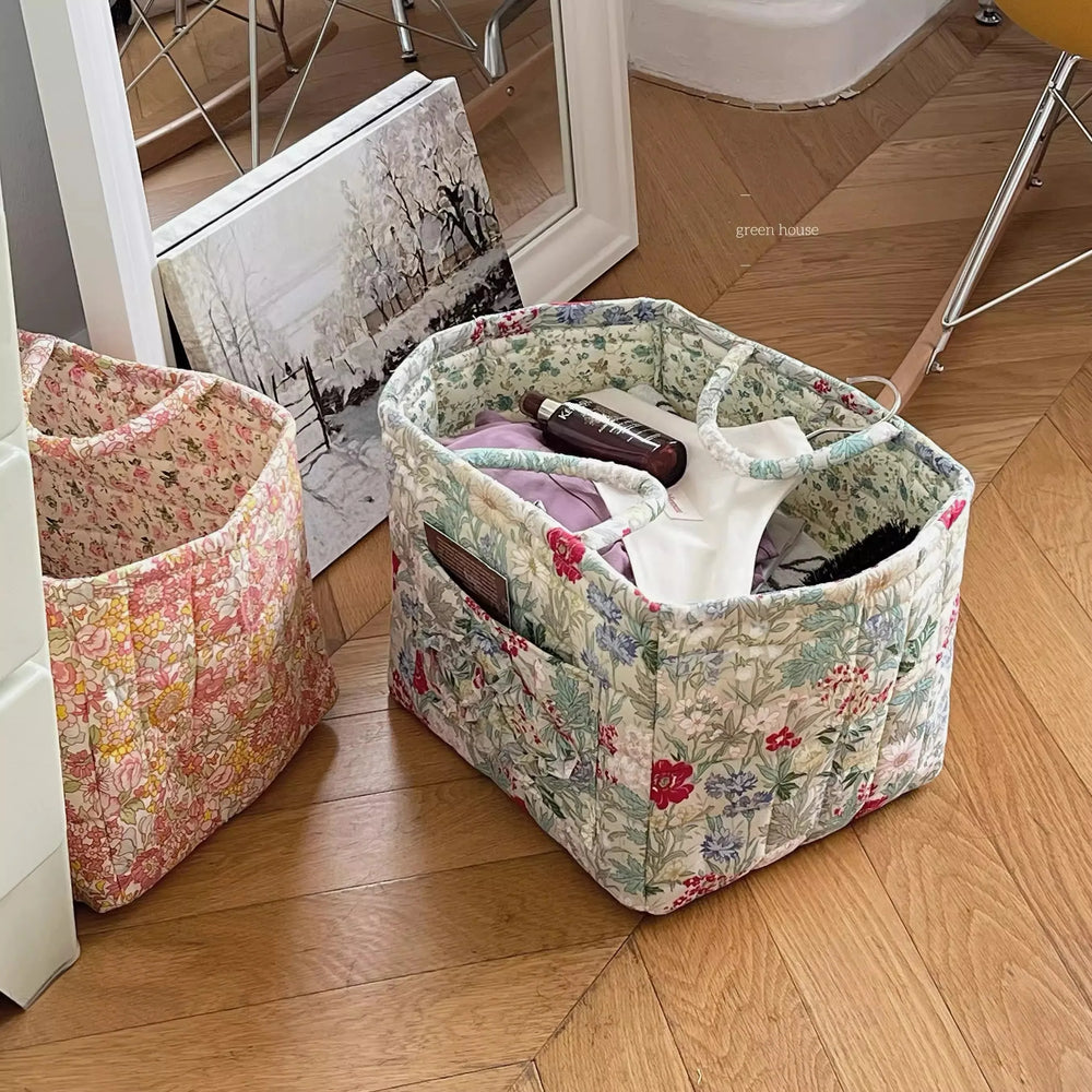 Floral fabric storage baskets on a wooden floor with items inside.