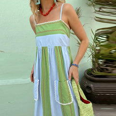 Woman wearing a green and white dress with lace details against a light green wall.