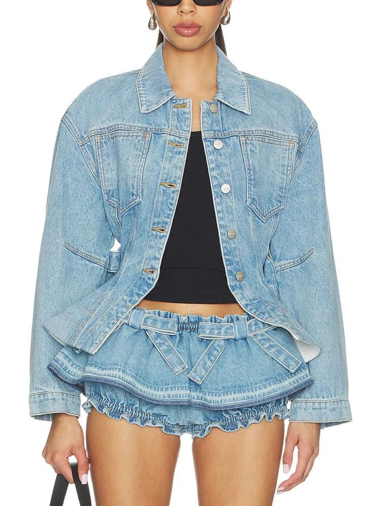 Model wearing a denim peplum jacket with belt and ruched shorts, showing torso