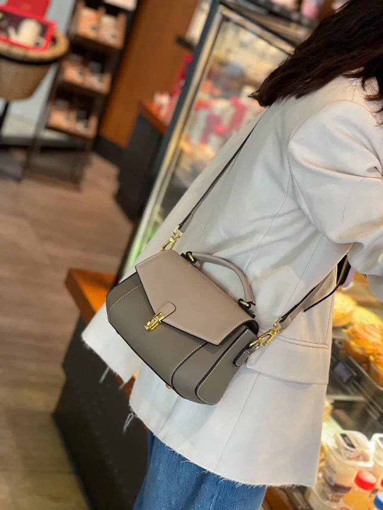 Person holding a gray handbag in an indoor setting