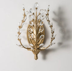 Decorative wall sconce with gold and crystal design on a light gray background