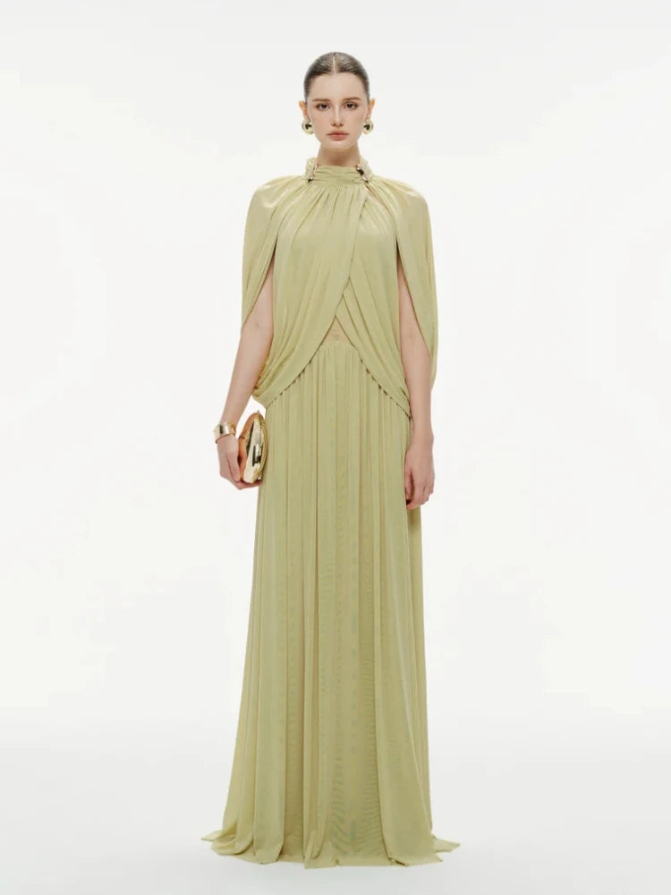 Woman wearing a light green evening gown with a cape on a white background