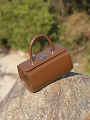 Brown leather top handle bag on a rock