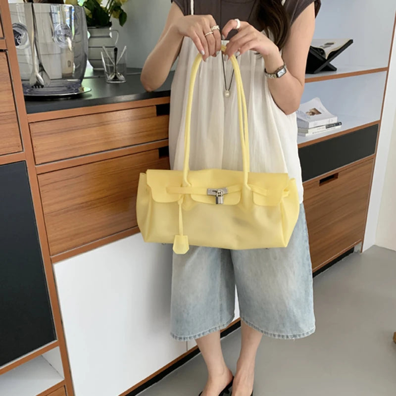 Yellow PVC tote bag with silver hardware held by a person.
