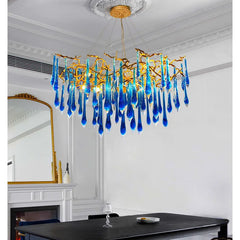 Blue glass chandelier hanging in a room with white walls and a fireplace.