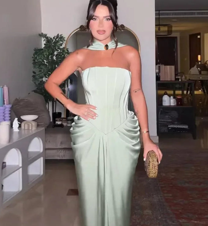 Woman in a light green strapless dress holding a clutch in a living room setting.