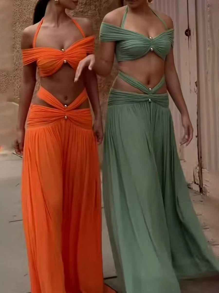 Two models wearing matching green and orange halter neck ruched crop top and cutout skirt sets
