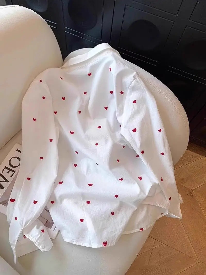 White shirt with red heart patterns on a white chair.