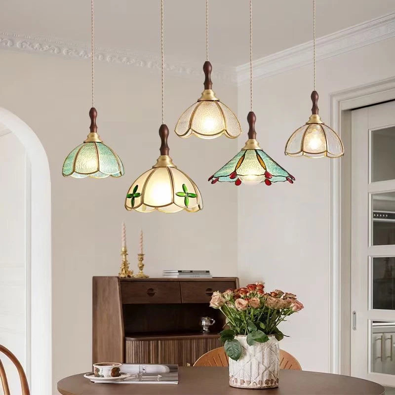 Set of Tiffany-style green stained glass pendant lights with red drops in cozy dining room