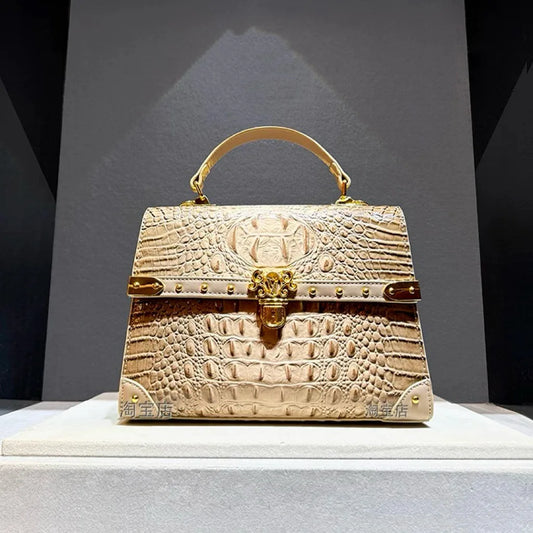 Structured crocodile embossed leather top handle bag in apricot with gold hardware.