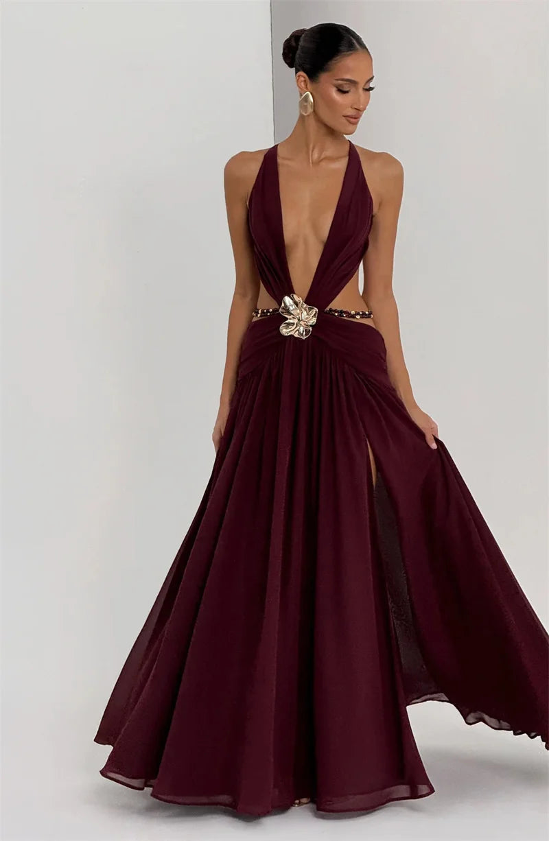 Woman wearing a burgundy evening gown with a deep neckline and gold embellishments on a white background