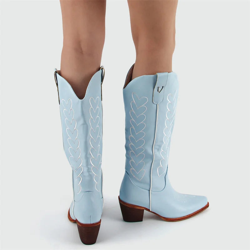 Light blue cowboy boots with brown accents worn by a person on a white background