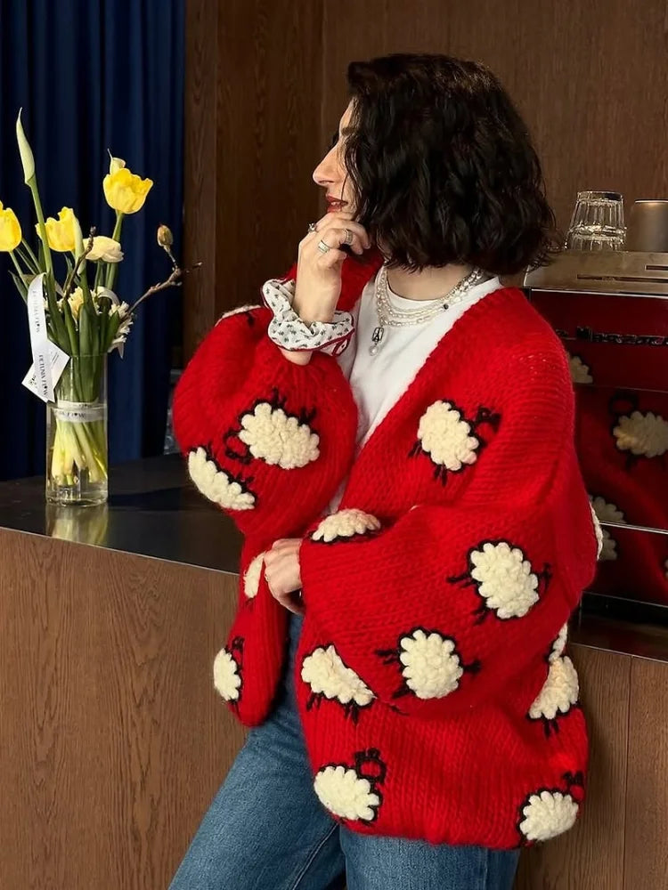 Person wearing a red cardigan with white floral patterns in an indoor setting.
