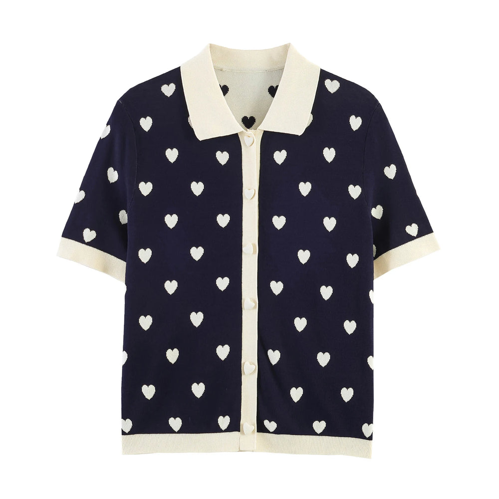 Navy knit polo top with white heart jacquard pattern, short sleeves, and contrasting collar.