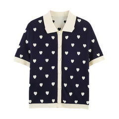 Navy knit polo top with white heart jacquard pattern, short sleeves, and contrasting collar.