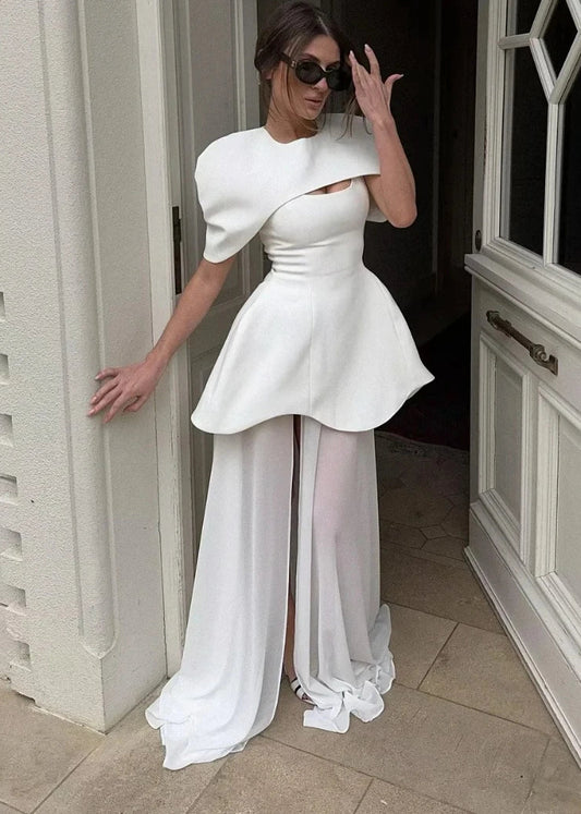 Woman in a white dress with puffed sleeves and sheer panels standing in a doorway.