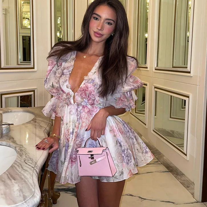 Woman in a floral dress holding a pink handbag in a marble bathroom.