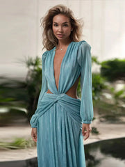 Woman wearing a light blue dress with long sleeves and a cut-out design, standing outdoors.