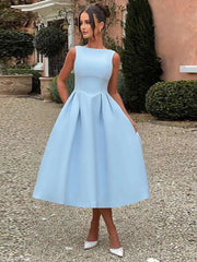Woman wearing a light blue dress standing outdoors.